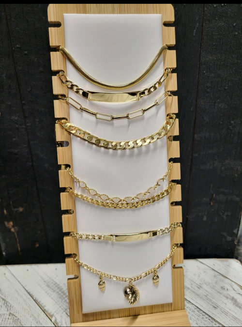 Eight gold bracelets on a bracelet holder. One of the bracelets have gold charms
