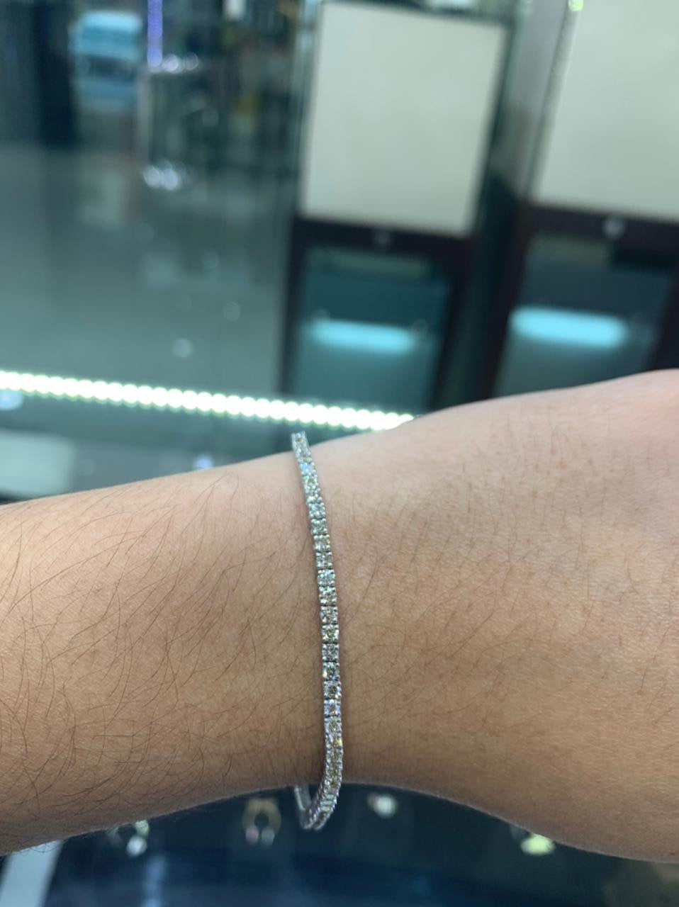 2.50 carat diamond tennis bracelet set in 18k white gold, worn on a woman's wrist. The wrist is turned outward,