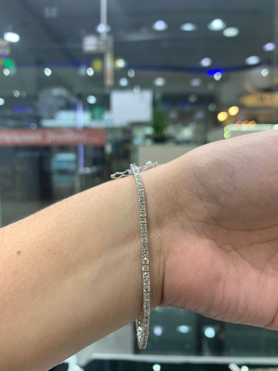 2.50 carat diamond tennis bracelet set in 18k white gold, worn on a woman's wrist. The wrist is turned inward.